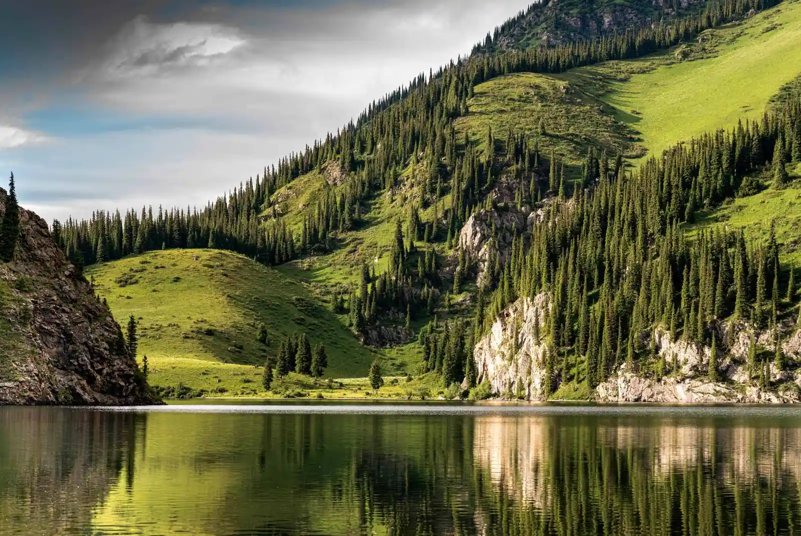 Scenic view of alpine lake and green mountains reflecting in water, Kolsay National Park